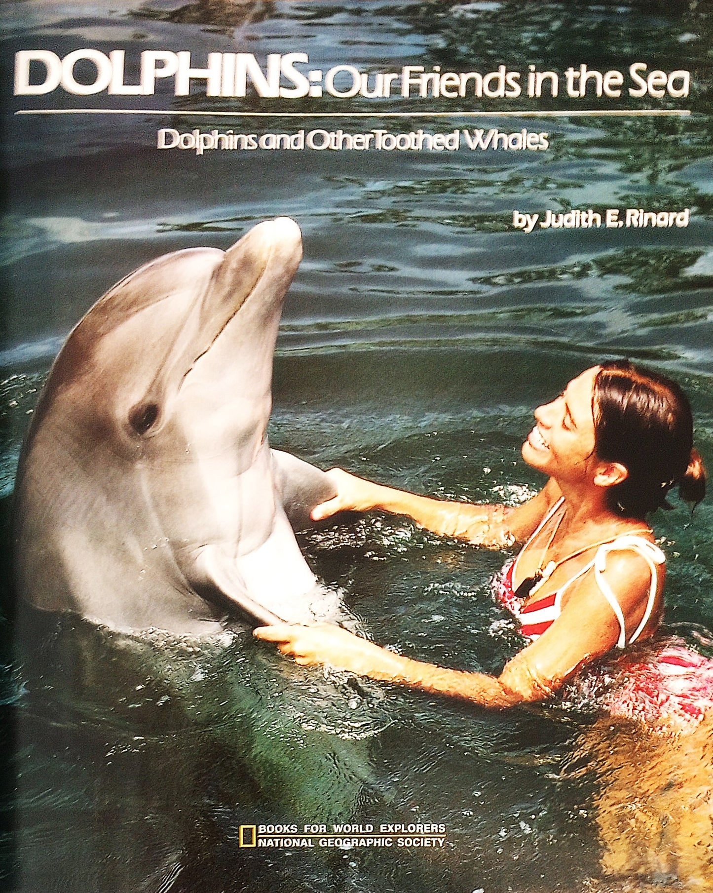 Title page of the book 'Dolphins: Our Friends in the Sea' showing photograph of a dolphin in the pool with a trainer.