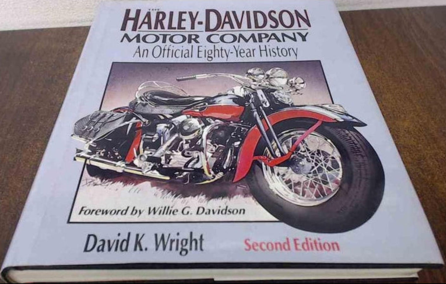 Book titled 'Harley-Davidson Motor Company: An Official Eighty-Year History' by David K. Wright on a wooden surface.