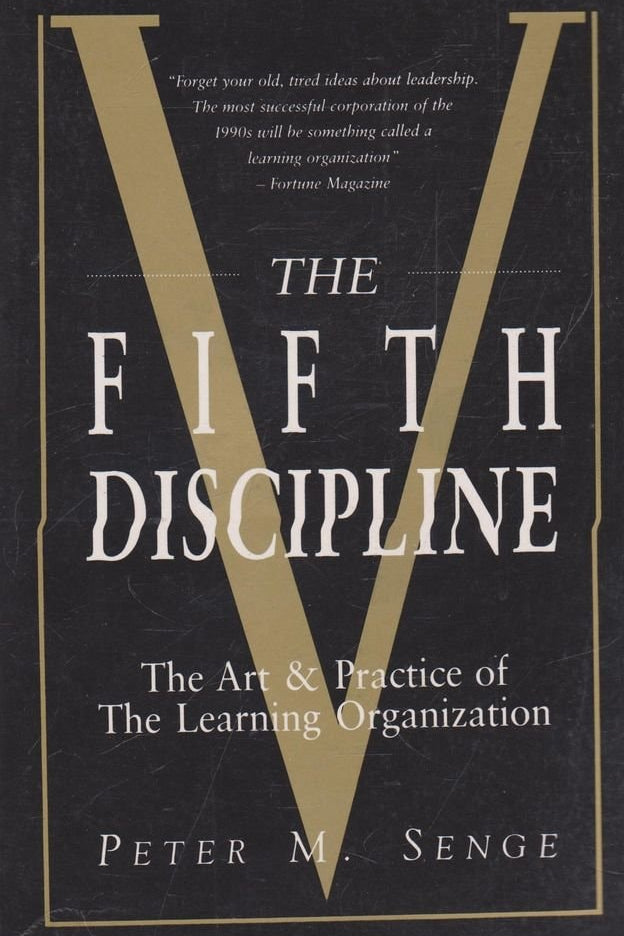 Book cover of 'The Fifth Discipline' by Peter M. Senge with a large gold 'V' on a black background.