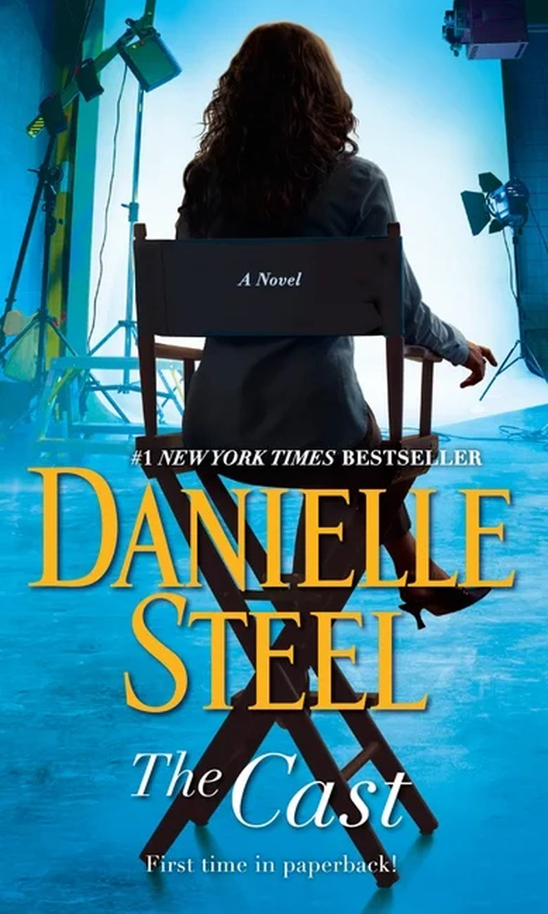 Book cover of 'The Cast: A Novel' by Danielle Steel, featuring a woman in a chair with a blue and yellow backdrop, indicating a scene likely from a television show or movie.