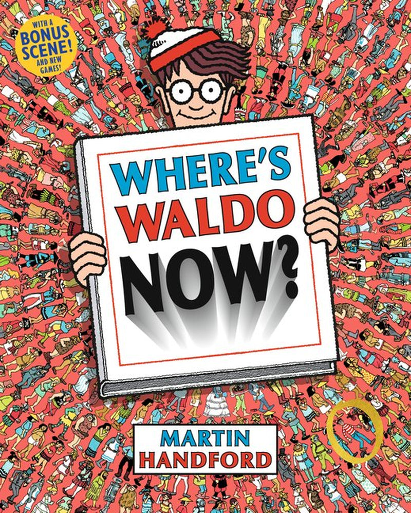 Cover of the children's book 'Where's Waldo Now?' by Martin Handford, featuring a cartoon version of the main character Waldo holding a newspaper with the title and the text 'BONUS SCENE! NEW GAMES!!'.