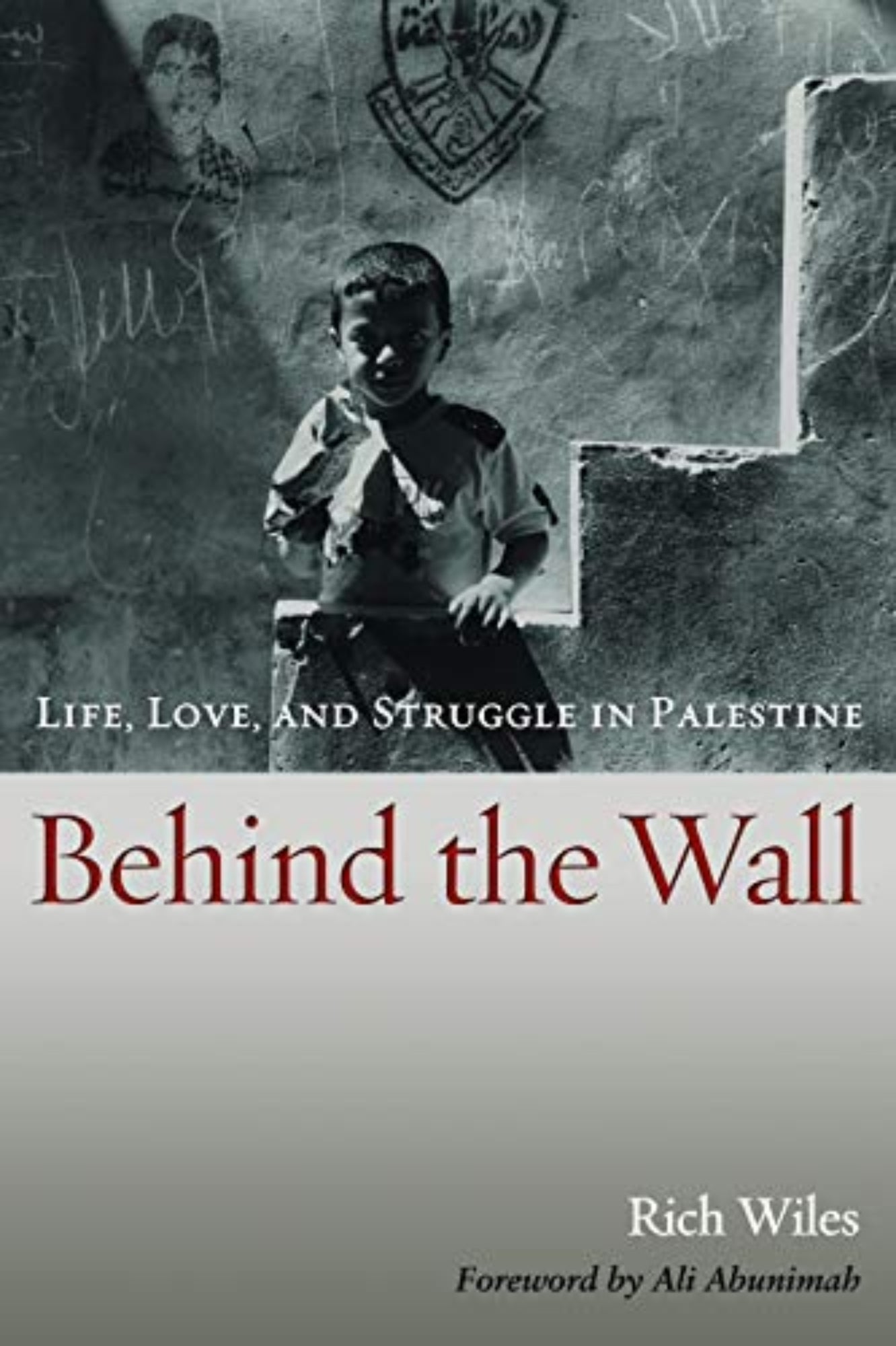 Book front cover of "Behind the Wall: Life, Love, and Struggle in Palestine" by Rich Wiles. Featuring an image of a young Palestinian child standing against the border wall.