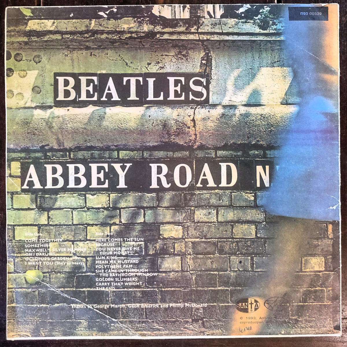 Beatles Abbey Road vinyl record sleeve, showing the iconic brick wall artwork with the band name 'BEATLES' and album title 'ABBEY ROAD' in large white lettering. A blue translucent sleeve edge is visible on the right side.
