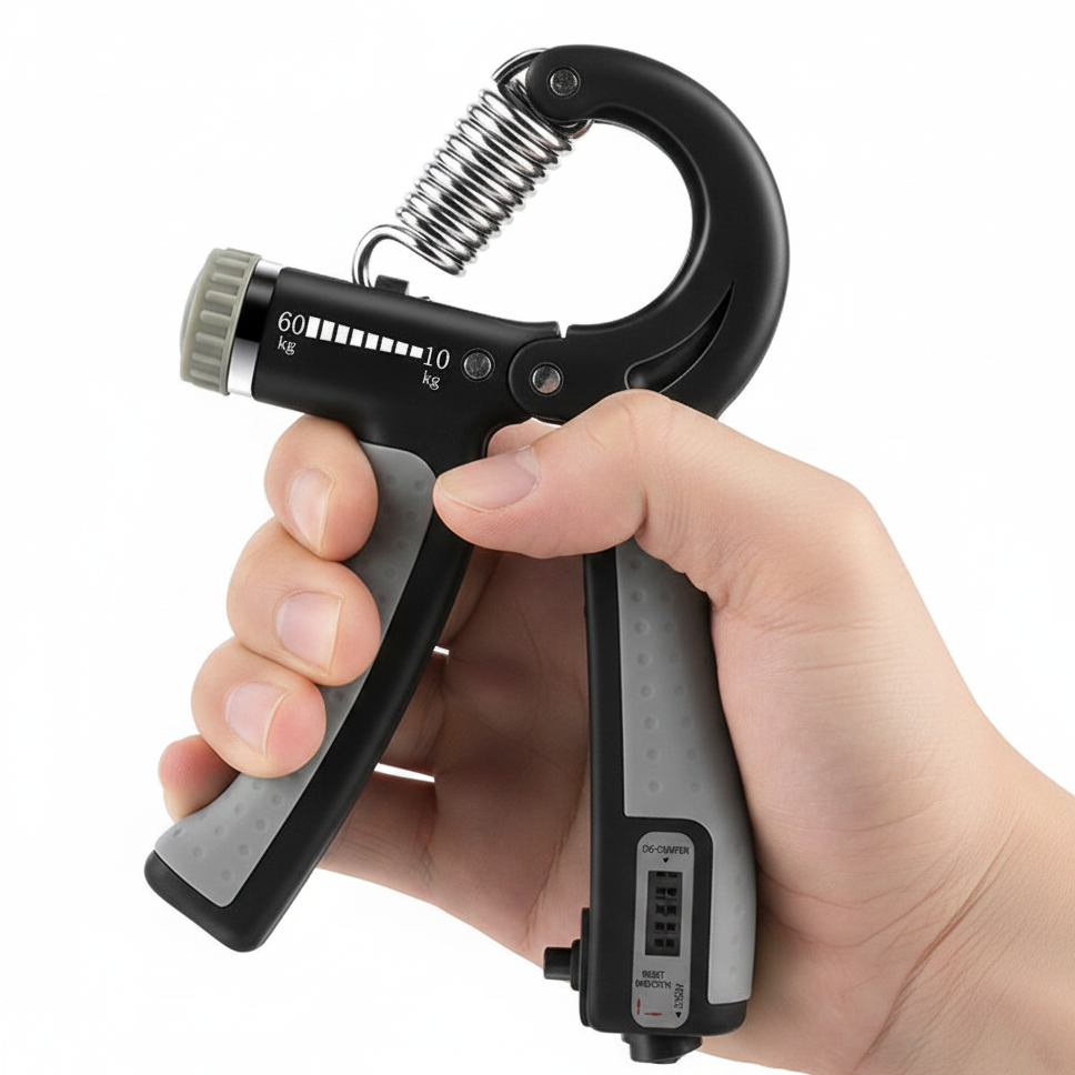 A hand grip strengthener held by a hand against a plain white background. The device is primarily black with gray textured grips, a silver metal spring, and a gray adjustment dial with white markings.
