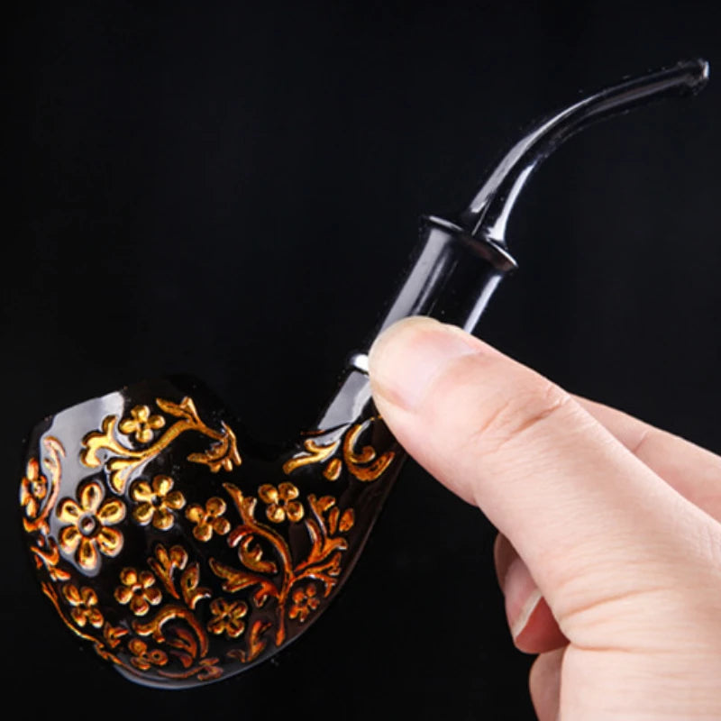 Hand holding a decorative smoking pipe with intricate designs against a black background