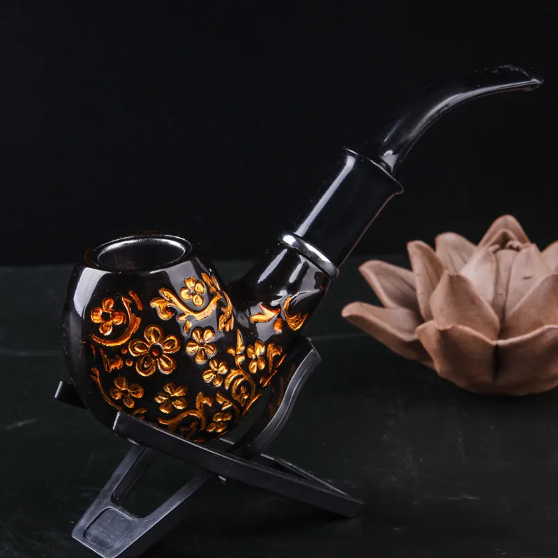 Decorative black pipe with gold floral patterns on a dark background