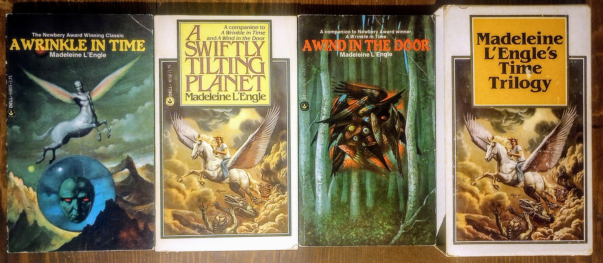 Three books and case cover from Madeleine L'Engle's Time Trilogy on a wooden surface.