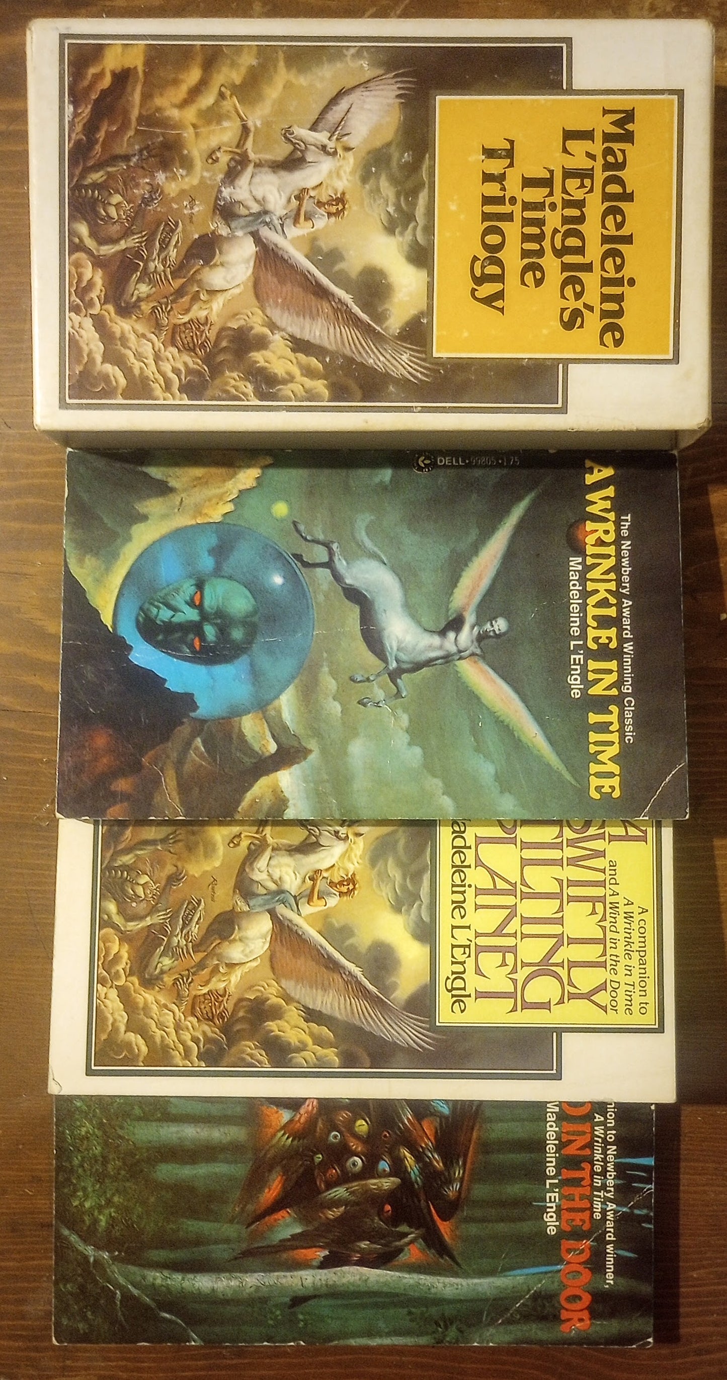 Collection of books from Madeleine L'Engle's Time Trilogy on a wooden surface.