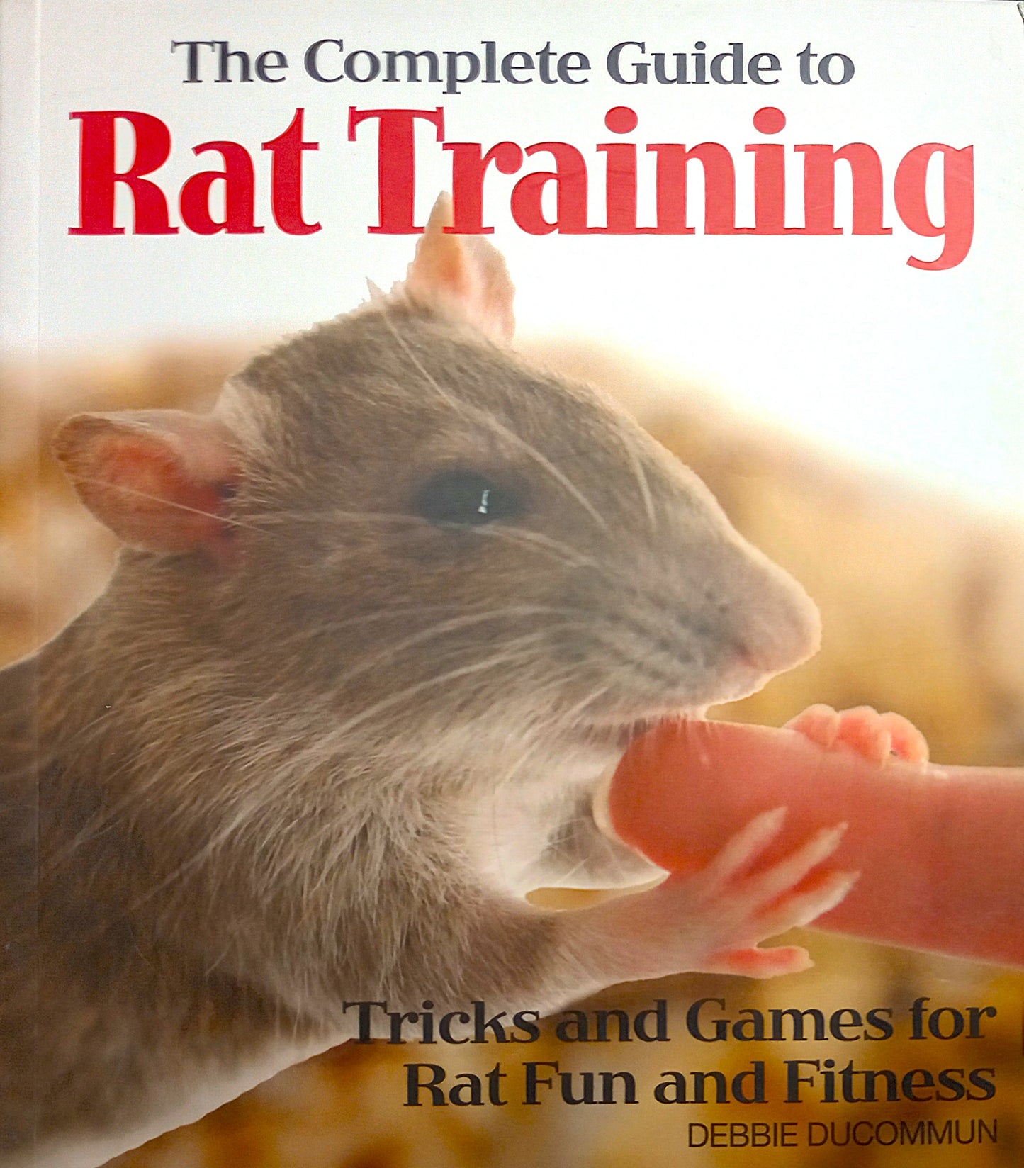 Book cover of 'The Complete Guide to Rat Training' with a rat and carrot on a blurred background