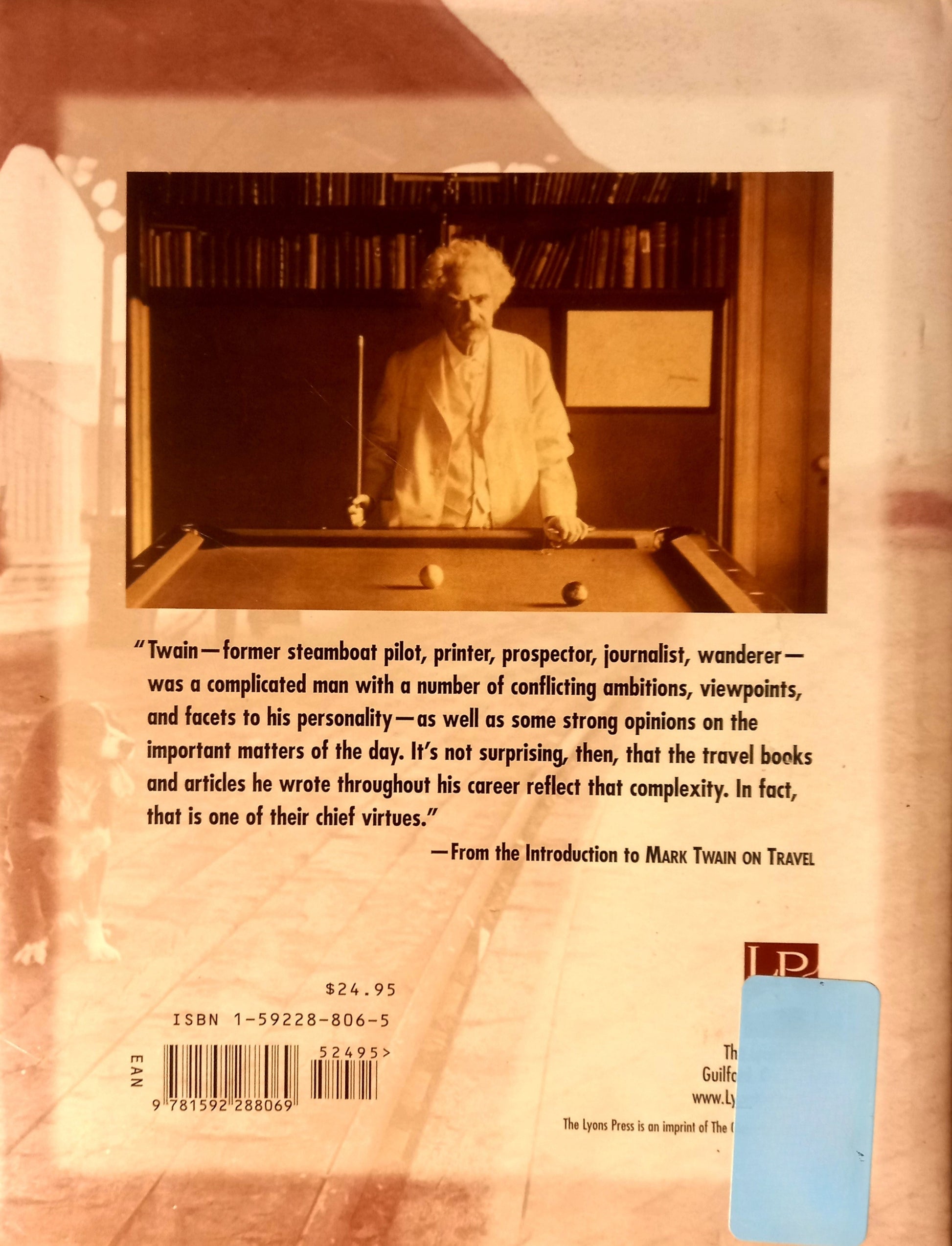 Book back cover of "Mark Twain on Travel" by Mark Twain and Edited by Terry A. Mort. Featuring a centered portrait of Twain standing over a pool table with a pool stick in hand with the synopsis, barcode and ISBN number below.