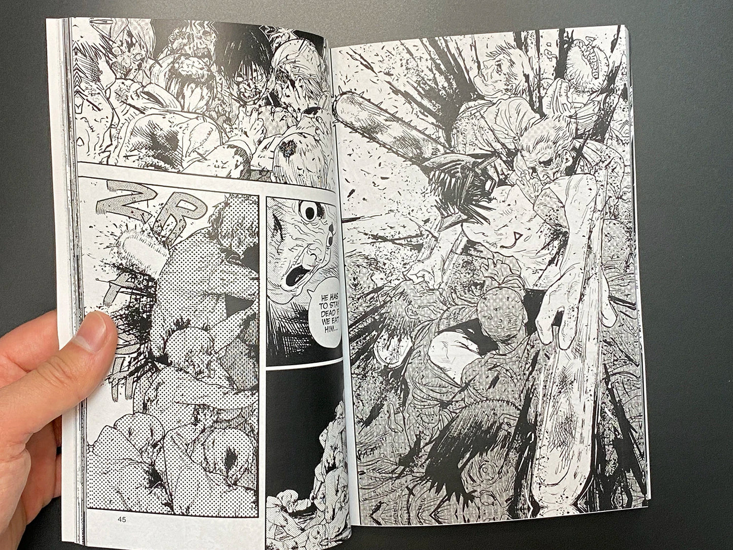 Comic book open to a page with black and white illustrations on a dark background