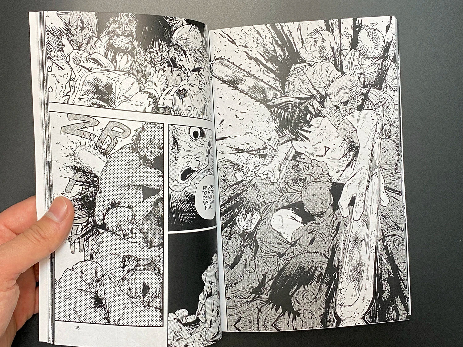 Comic book open to a page with black and white illustrations on a dark background