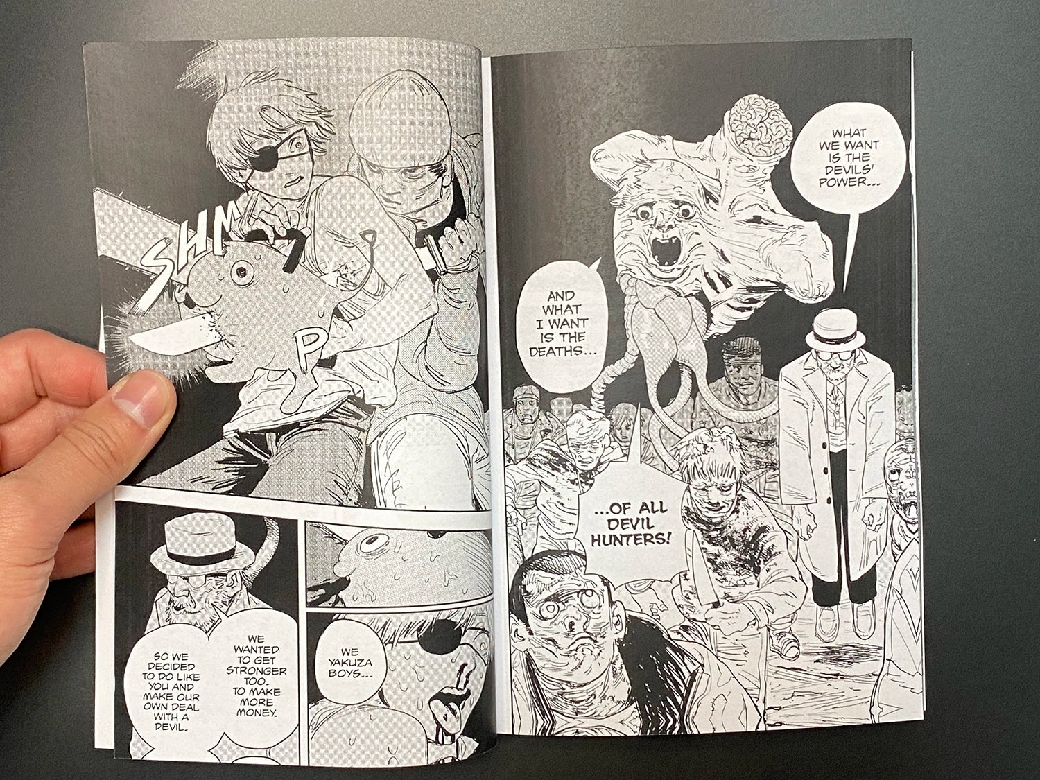 Open comic book with black and white illustrations on a dark background