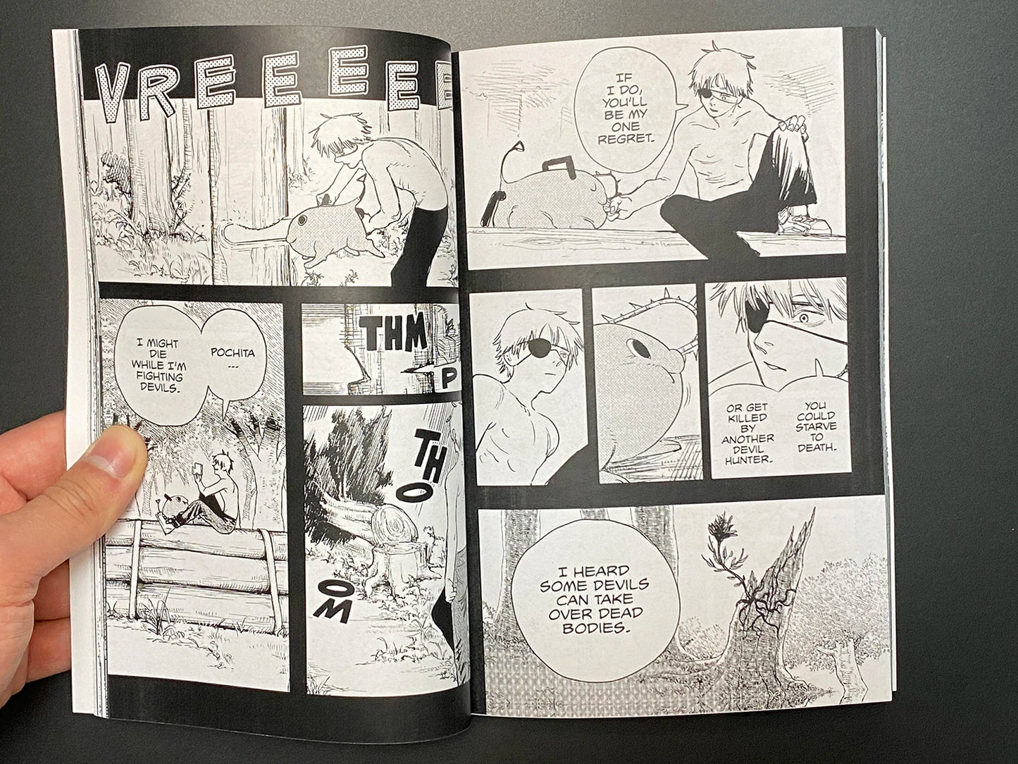 Open comic book with black and white illustrations and text on a dark background