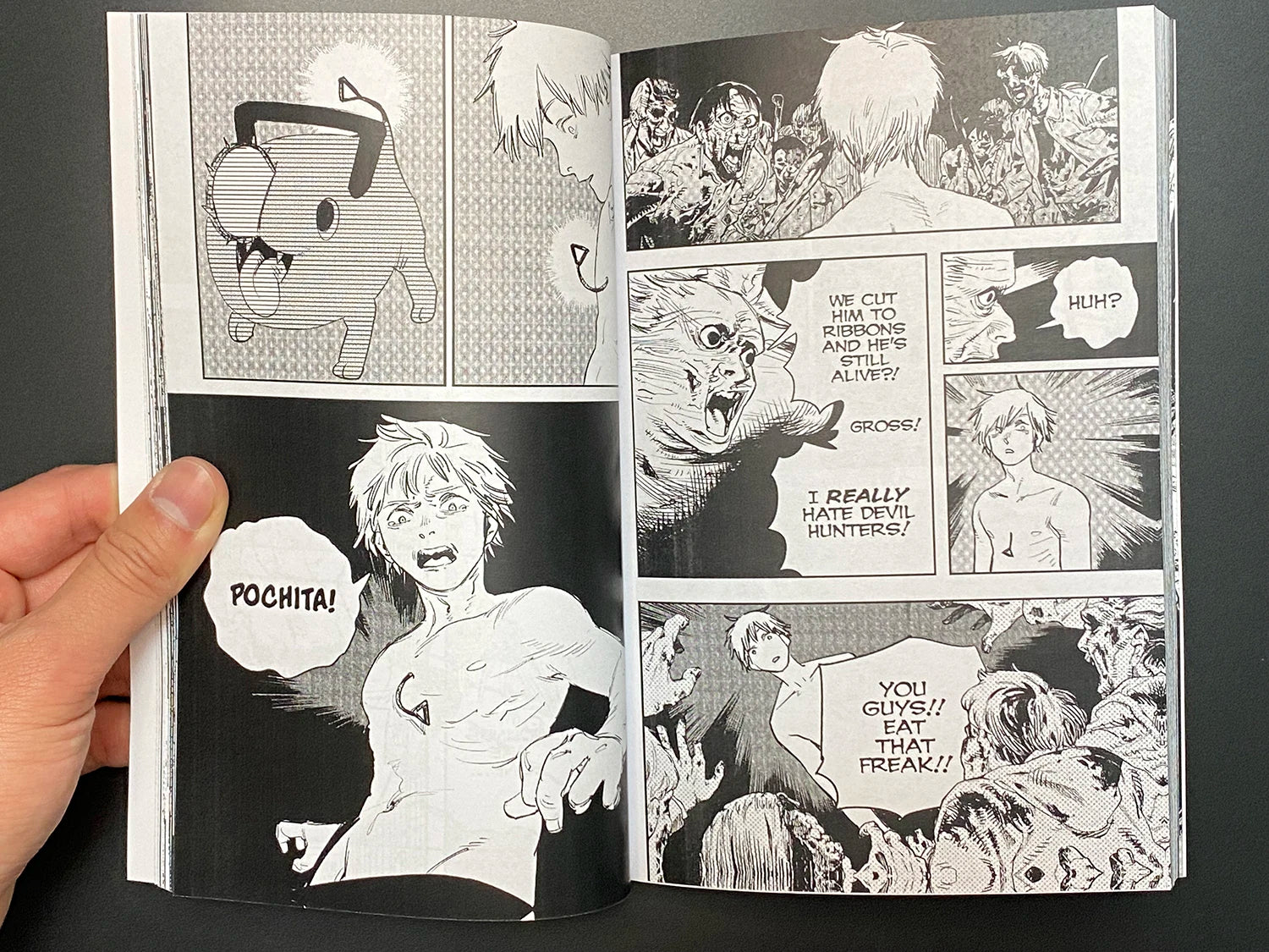 Open manga book showing black and white comic panels with expressive characters and text bubbles.
