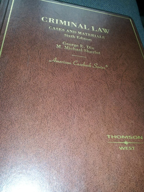 Brown leather-bound book titled 'Criminal Law' with embossed text on a wooden surface.