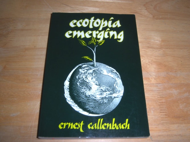 Book titled 'ecotopia emerging' by Ernest Callenbach on a wooden surface