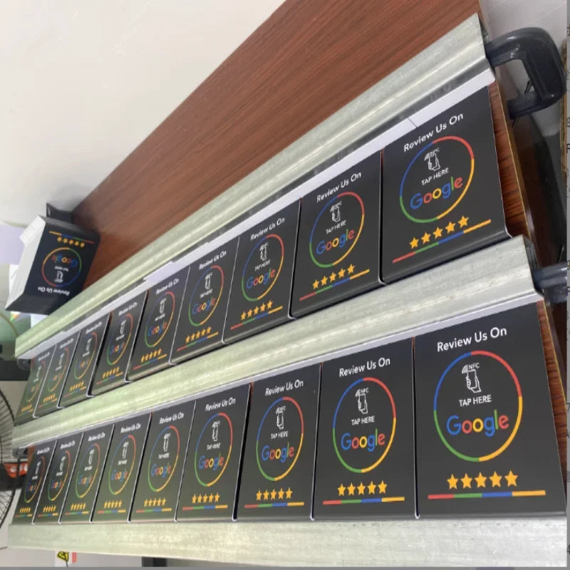Multiple 'Review Us On Google' signboards on a shelf with wooden and white background.
