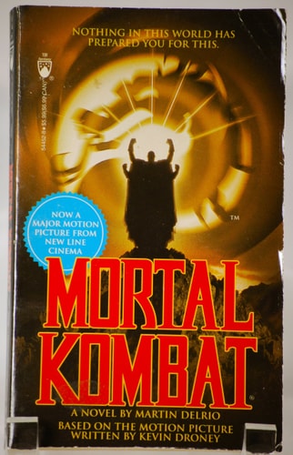 Book cover of 'Mortal Kombat' with a silhouette and glowing circle design.