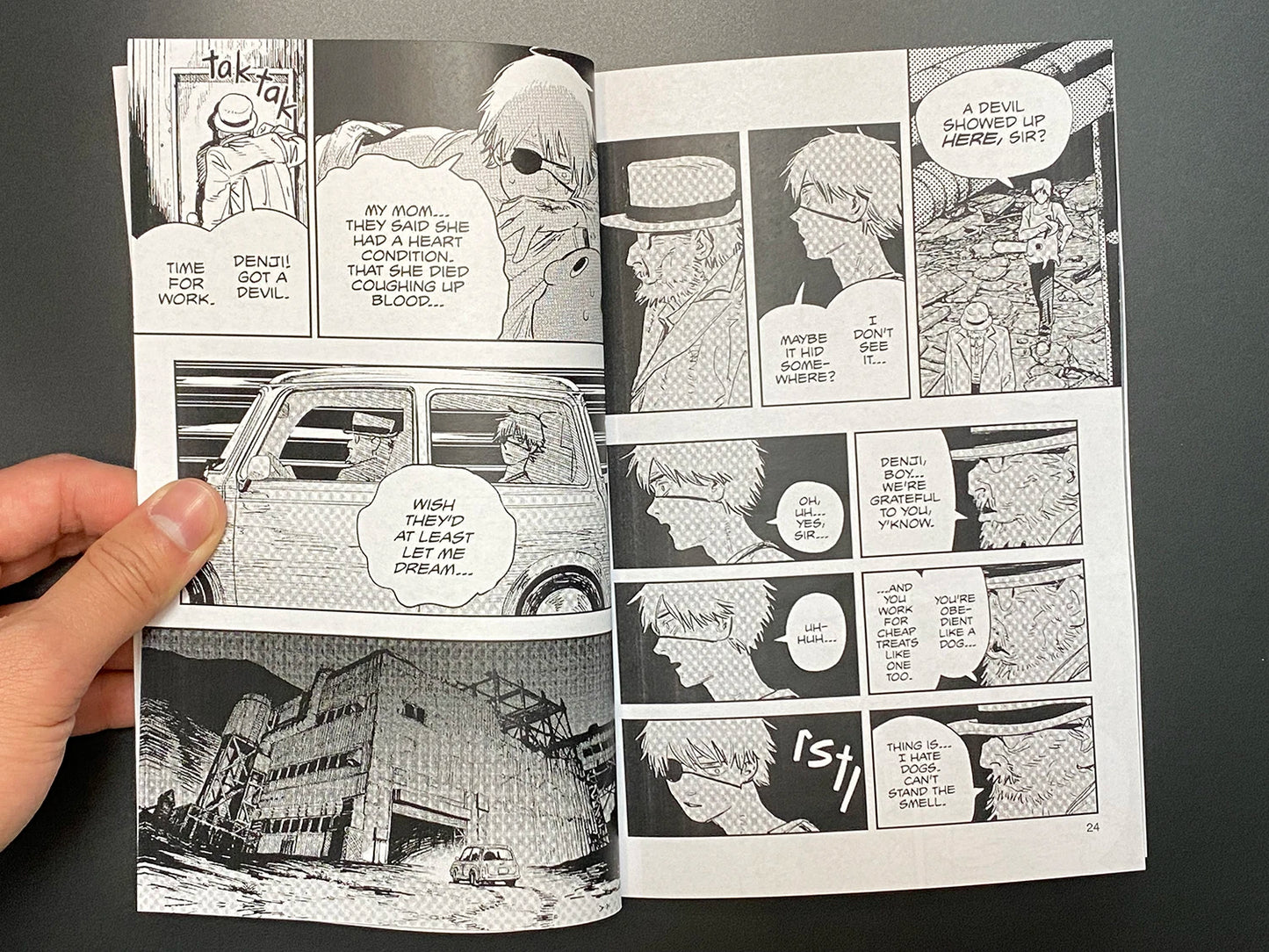 Comic book pages held open by a hand on a dark background