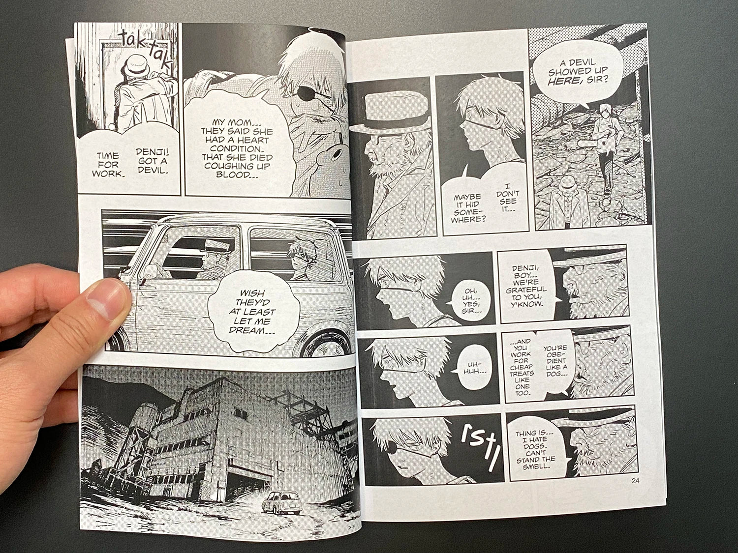 Comic book pages held open by a hand on a dark background