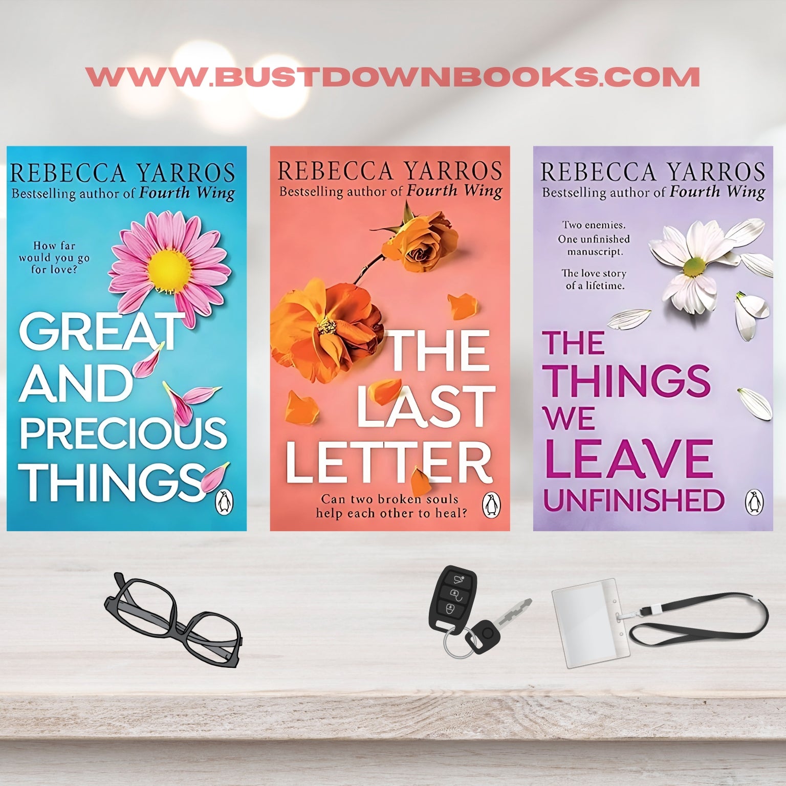 Three book covers by Rebecca Yarros on a white surface with glasses, keys, and a lanyard.