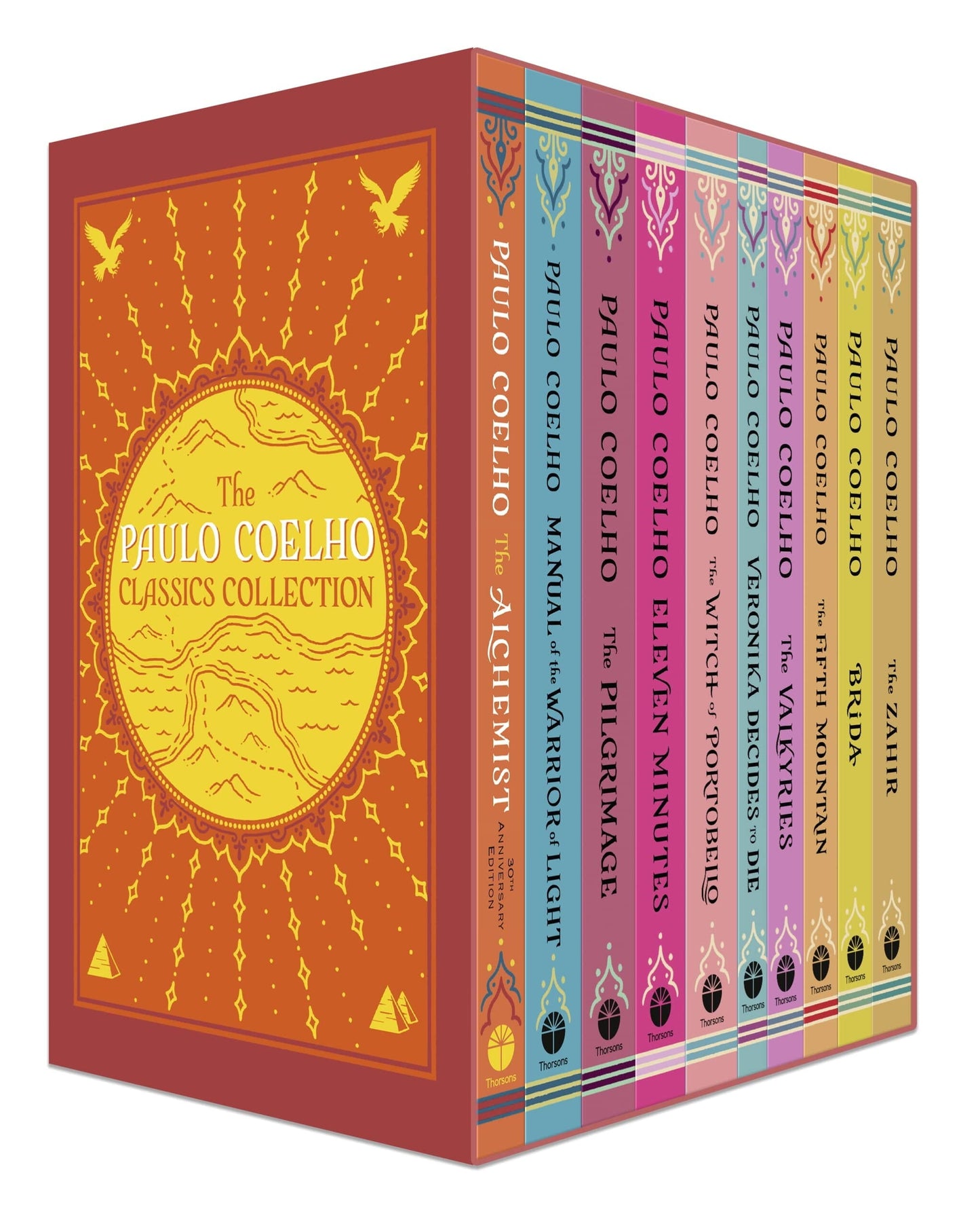 A box set of Paulo Coelho books with various titles displayed on the spines, including 'The Alchemist' and 'The Pilgrimage'. The box is primarily orange and red with a mountain design and the author's name.