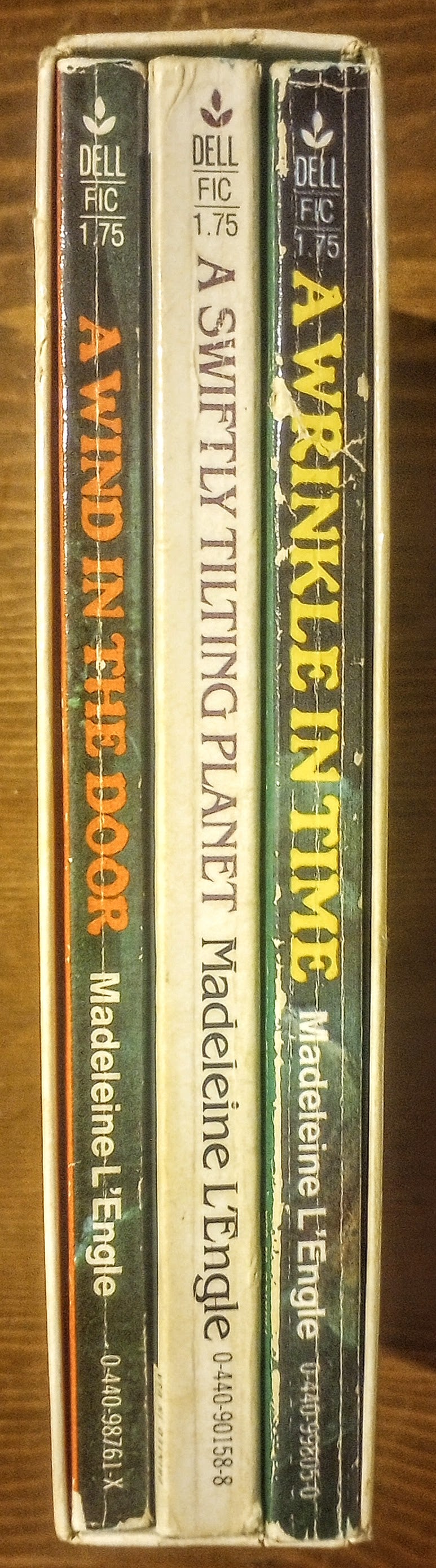 Three books from the 'A Wrinkle in Time' series by Madeleine L'Engle on a wooden surface.