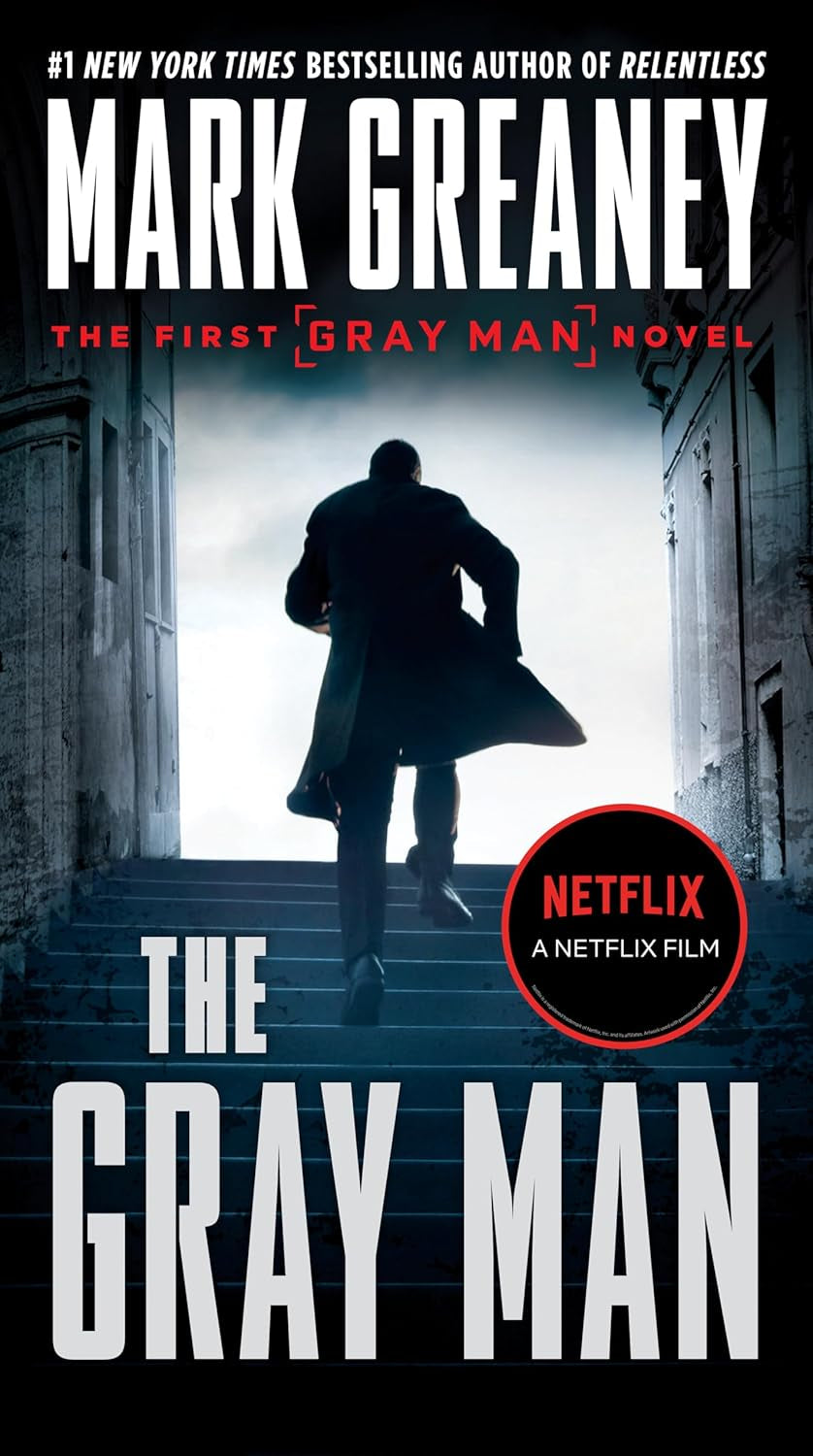 Book front cover of "The Gray Man" by Mark Greaney, featuring a man running up stairs in a coat.