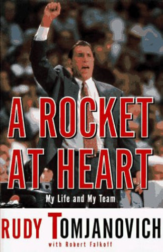 Book cover for 'A Rocket at Heart: My Life and My Team' by Rudy Tomjanovich, featuring a photo of a man in a suit raising his fist on a basketball court, with large red title text and a white band at the bottom.
