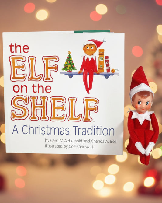 The image shows a keepsake box gift set of 'The Elf on the Shelf: A Christmas Tradition' which includes a boy scout elf with light skin tone and a red suit, along with a children's book.