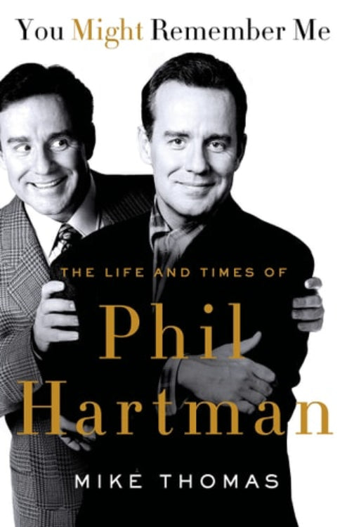 The cover of the book 'You Might Remember Me: The Life and Times of Phil Hartman' by Mike Thomas, features two side-by-side images of Phil Hartman in different poses, with the title and author's name, Mike Thomas, prominently displayed.