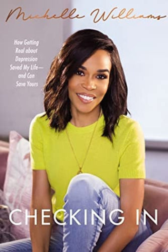 Book cover for 'Checking In' by Michelle Williams, featuring the author smiling with dark shoulder-length hair wearing a bright yellow-green top and light blue jeans, seated indoors with pillows in the background.