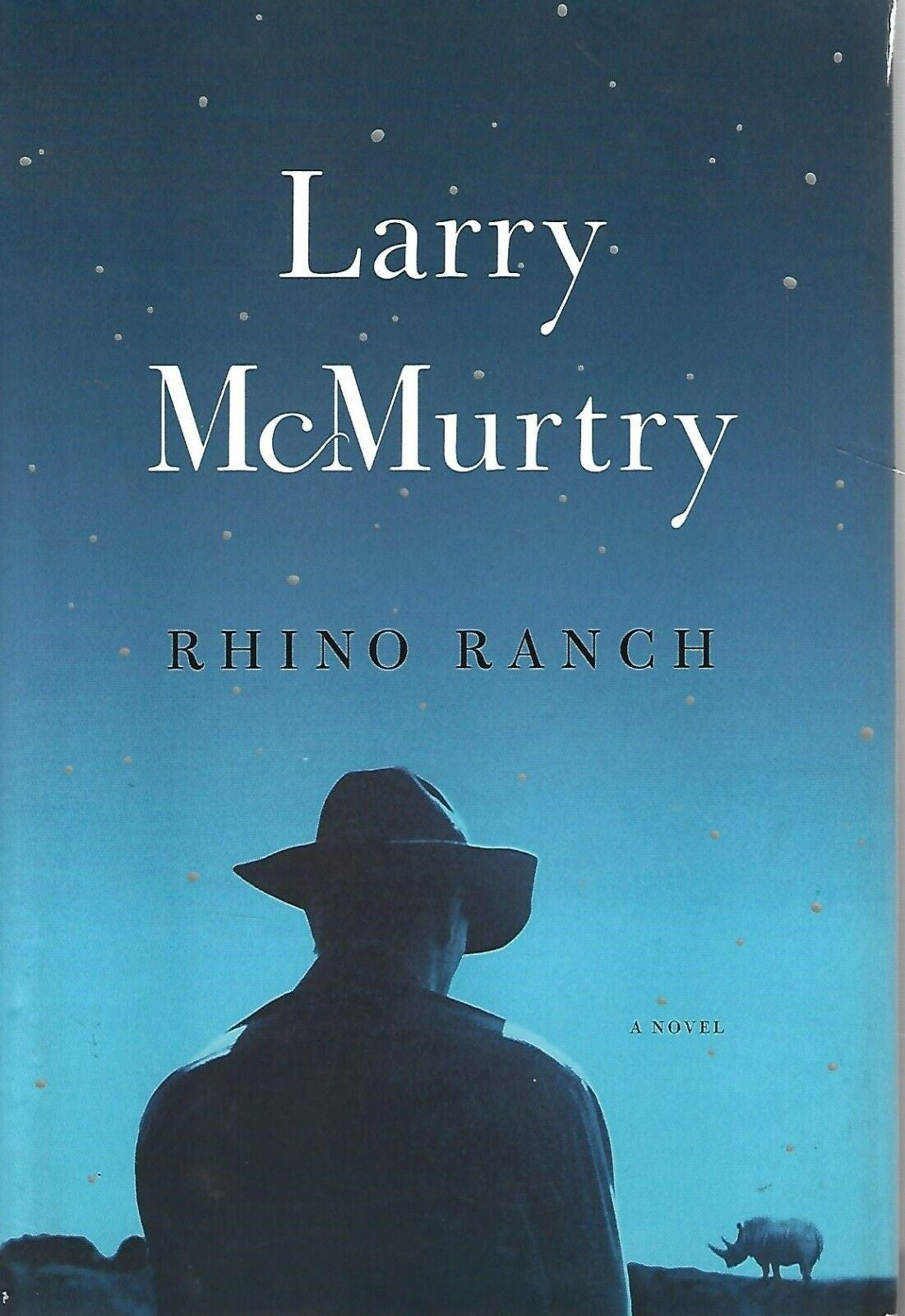 Cover of the book 'Rhino Ranch' by Larry McMurtry featuring a silhouette of a man wearing a hat against a backdrop of a starry sky and a rhinoceros in the distance.