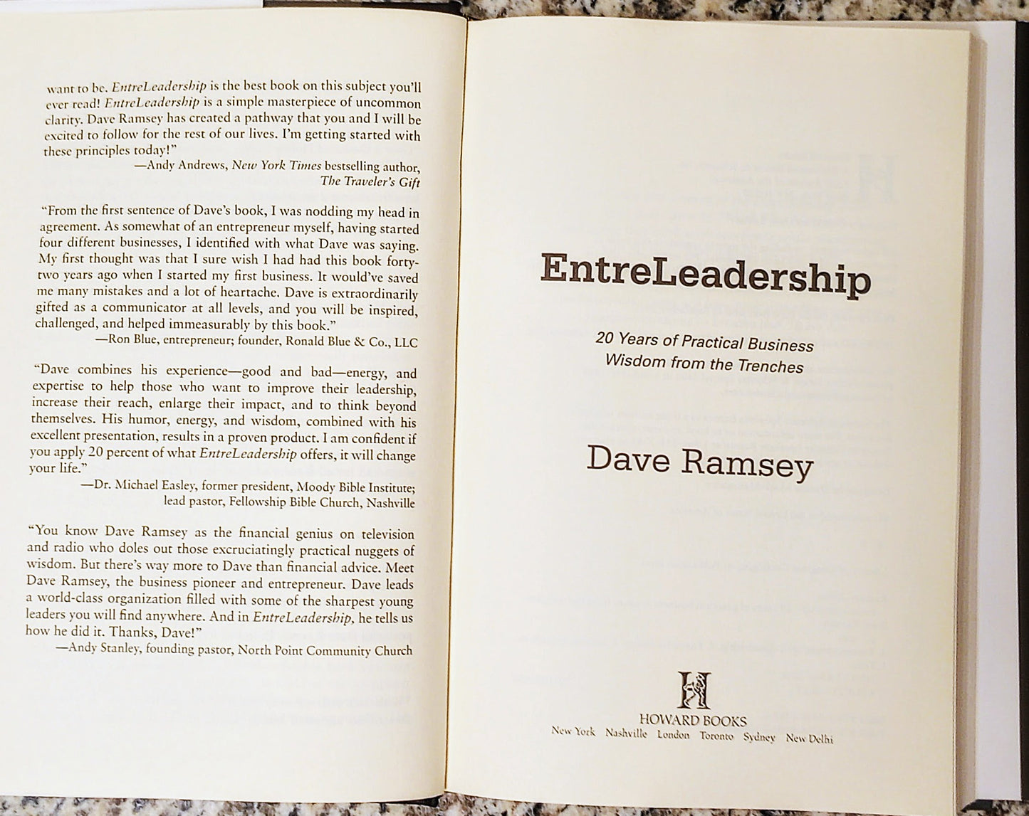 Open book displaying the title 'EntreLeadership' by Dave Ramsey on a marble surface.