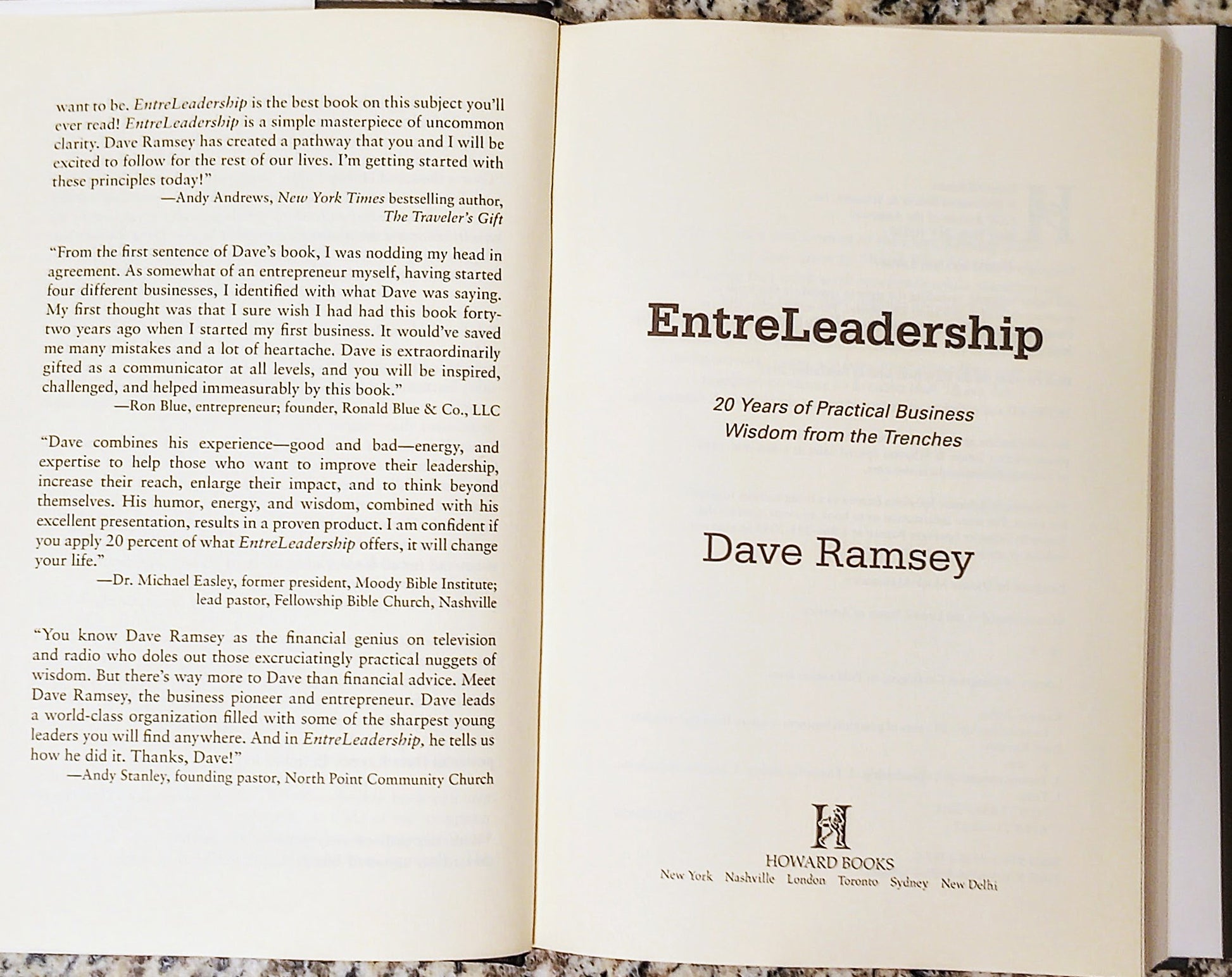 Open book displaying the title 'EntreLeadership' by Dave Ramsey on a marble surface.