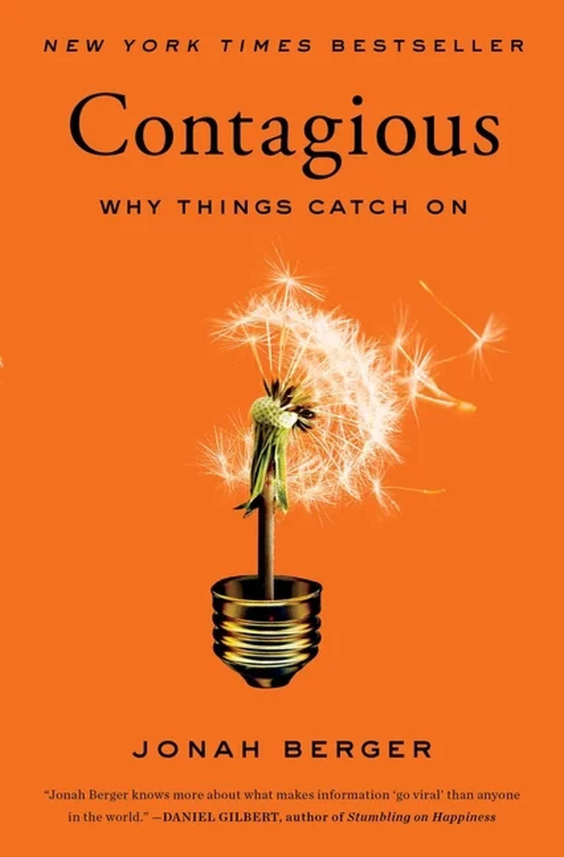 The cover of the book 'Contagious: Why Things Catch On' by Jonah Berger features a sparkler with a lit wick in a glass jar, symbolizing the spread of ideas, on an orange background.