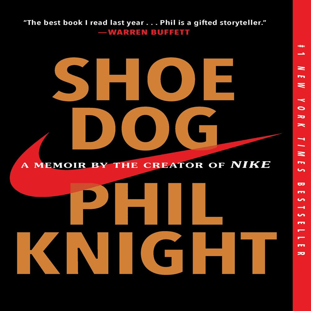 Book front cover of "Shoe Dog: A Memoir by the Creator of Nike [9781501135927]" by Phil Knight, featuring gold text over black and red (BRED), and the Nike swoosh across the center.