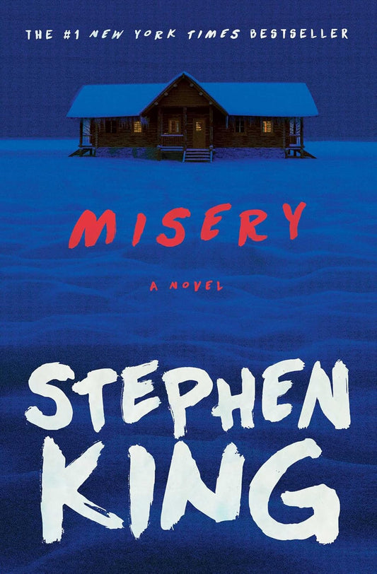This image features the cover of the novel "Misery" by Stephen King, a #1 New York Times bestseller. The cover design presents a striking and ominous scene with a dilapidated, dark-colored house situated on a desolate, wind-swept plain under a gloomy sky.