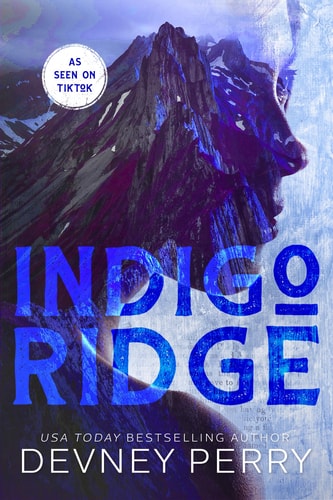 The image displays the cover of the book 'Indigo Ridge' by Devney Perry, which features a mountainous landscape with a prominent, rugged peak under a twilight sky. The title 'INDIGO RIDGE' is prominently shown in large, bold lettering in a blue hue, contributing to its mysterious and captivating aesthetic.