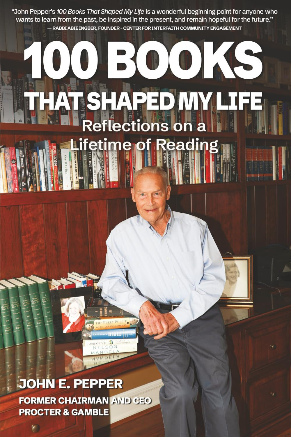 Book cover for '100 Books That Shaped My Life' by John E. Pepper, featuring a photo of the author seated in front of bookshelves with large white title text at the top.