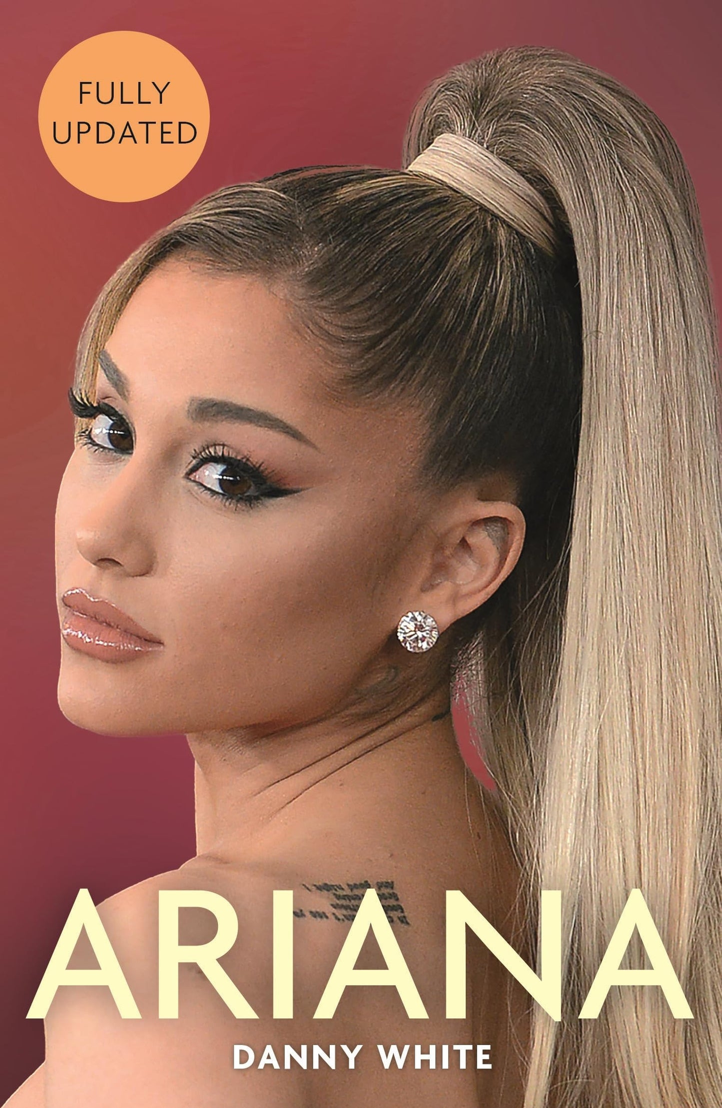 Book cover for 'Ariana' by Danny White, featuring a close-up portrait of Ariana Grande with blonde hair in a high ponytail against a dusty rose background, with a yellow 'Fully Updated' badge in the top left.