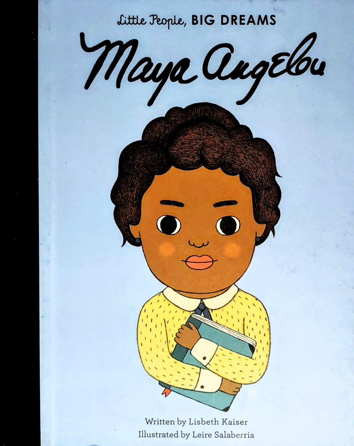 Children's book cover titled "Little People, BIG DREAMS" featuring the name "Maya Angelou" in large script above an illustrated young girl with dark curly hair, wearing a yellow sweater and holding books against a pale blue background.