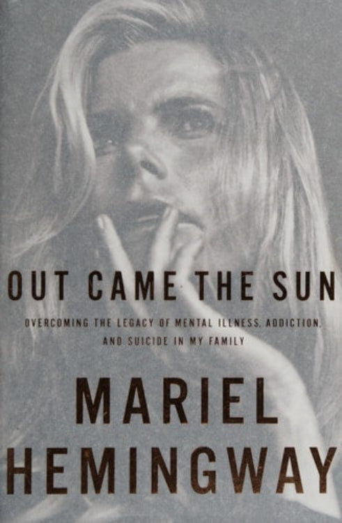 This image features the cover of the memoir titled "Out Came the Sun: Overcoming the Legacy of Mental Illness, Addiction, and Suicide in My Family" by Mariel Hemingway. The cover is designed with a muted, desaturated image of a young woman looking pensively to the side, adding a contemplative and serious tone to the piece.
