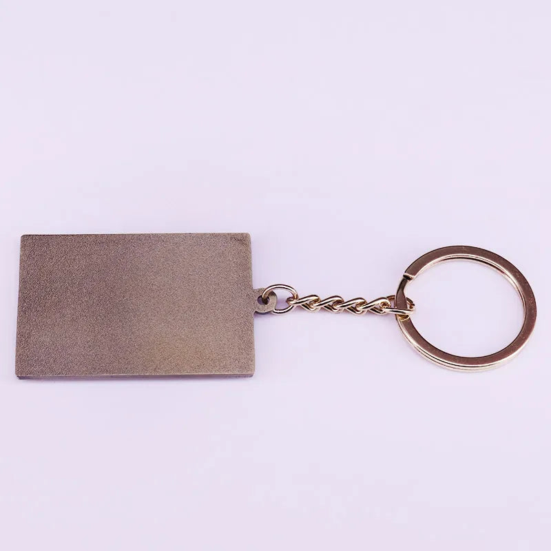 Jumanji keychain back with a rectangular metal tag on a light purple background