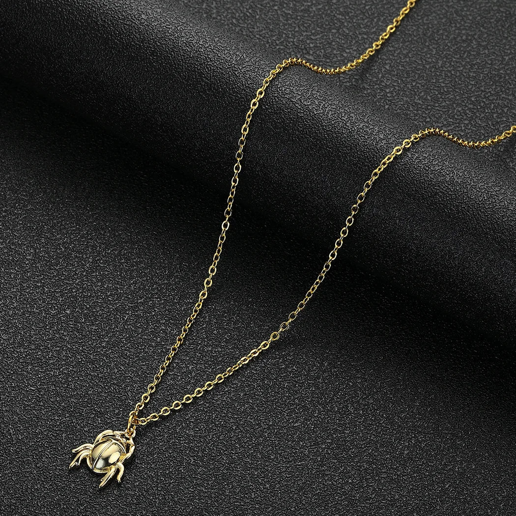Gold necklace with a crab pendant on a dark background