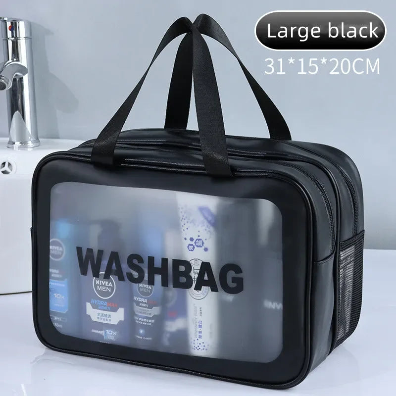 Black wash bag with transparent front panel showing toiletries, placed on a white surface with a bathroom background.