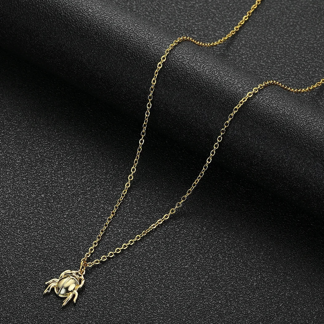 Gold crab pendant necklace on a dark background