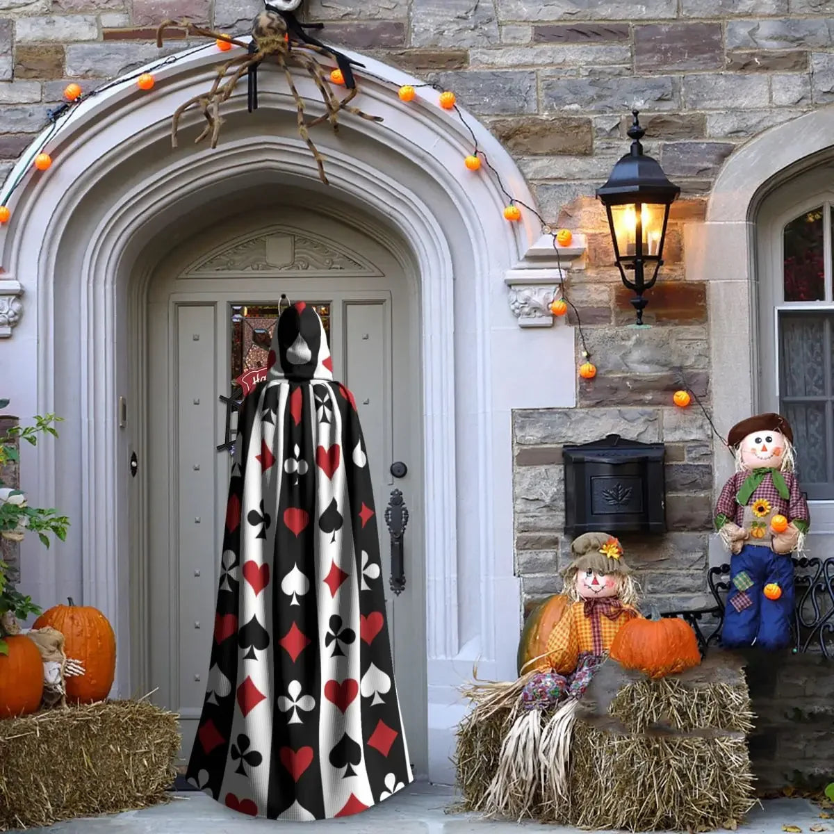 Halloween decorations including a card-themed figure, pumpkins, and scarecrows on a stone building entrance.