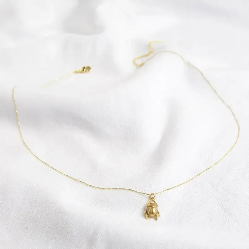 Gold necklace with a small pendant on a white background